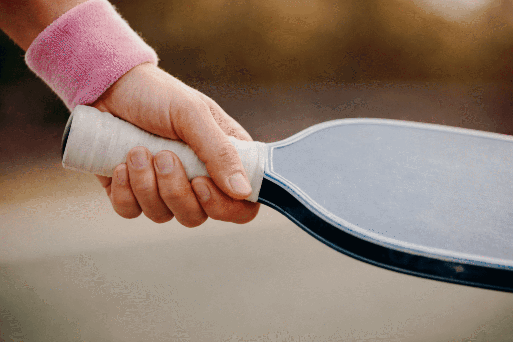 Close up of a hand loosely gripping a pickleball paddle showing relaxed finger position for a reset shot pickleball