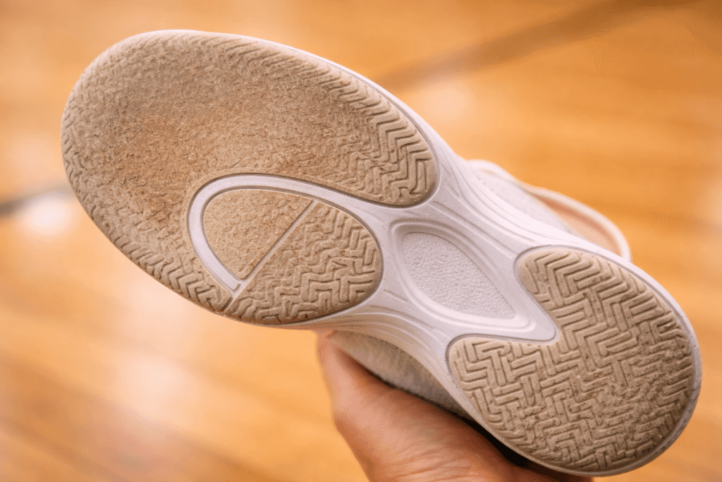 Bottom of a worn-out women's pickleball shoe with smooth tread worn away in the toe and ball area